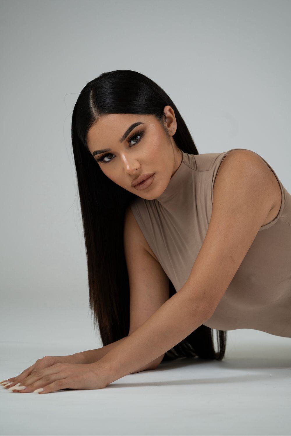 Medical weight loss patient model in a brown sleeveless mock turtleneck laying on the floor